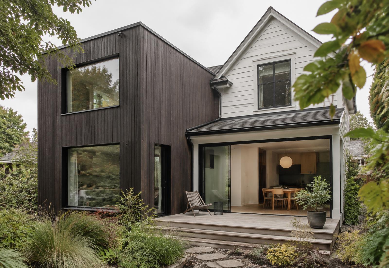 Modern rear addition clad in dark cedar joined to an older house