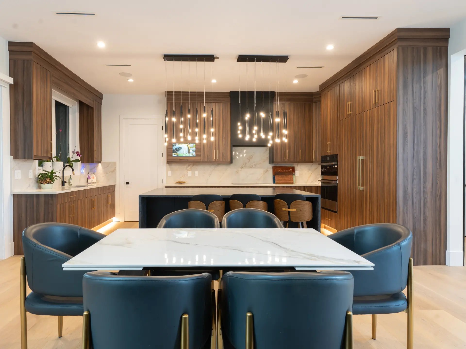 Kitchen and dining area with walnut cabinetry, marble table, and pendant lighting